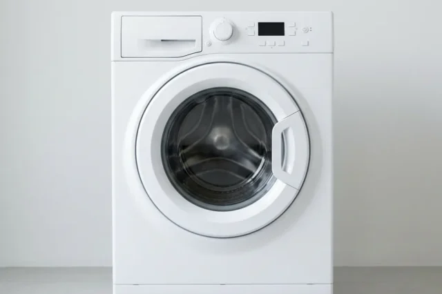 White front-load washing machine with a round glass door in a bright home laundry area.
